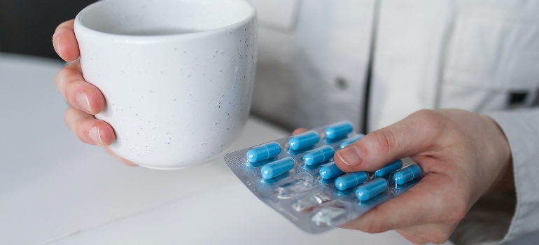 A woman holding blue pills and a cup