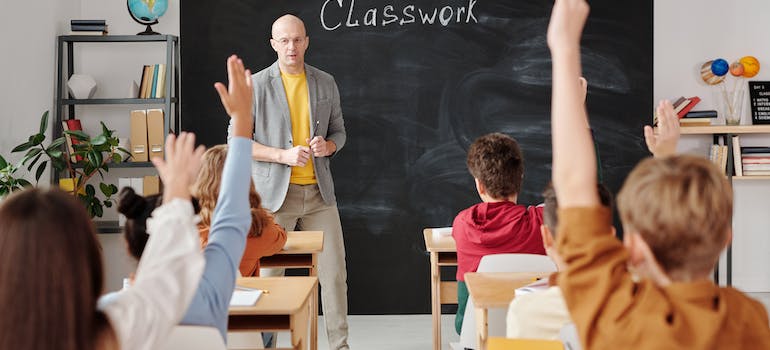 Children raising their hands to answer the teacher's question