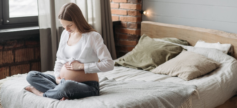 A pregnant woman sitting on a bed