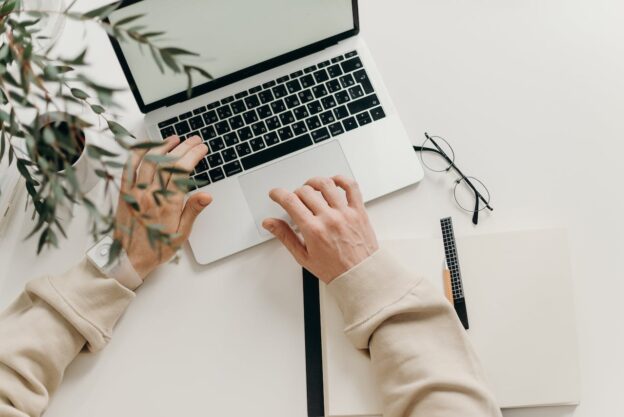 A person using a laptpo to write a review