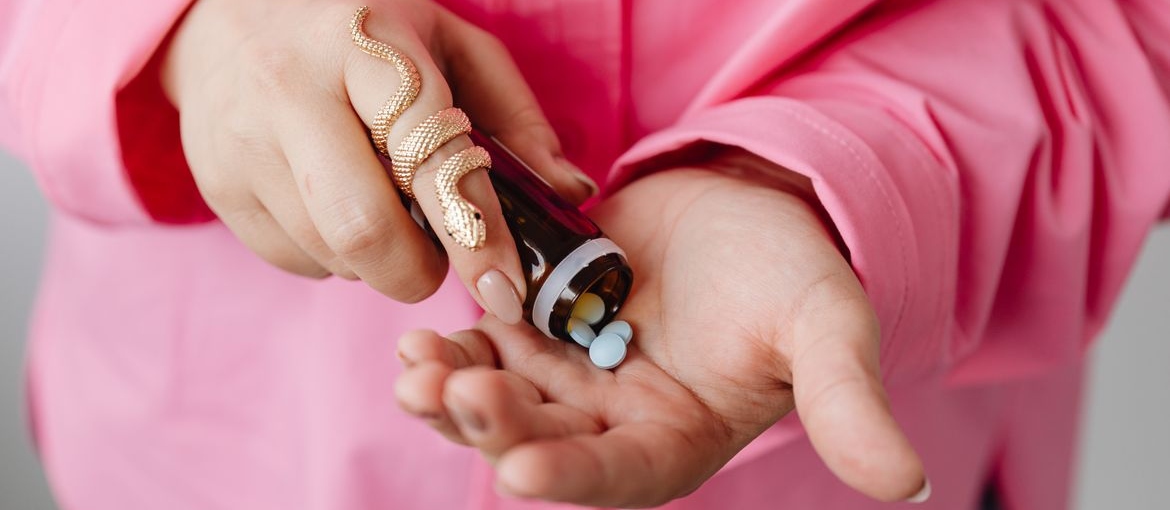 Woman putting pills into her hand.