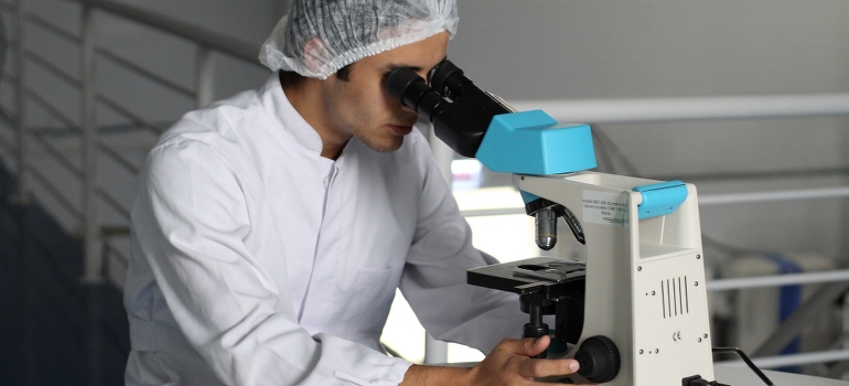 A man doing research studies related to ketamine therapy in WV on a microscope.