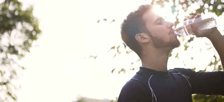 A man quenching his thirst with a bottle of water, emphasizing the importance of self-care.