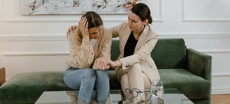 Two women sitting on a green sofa