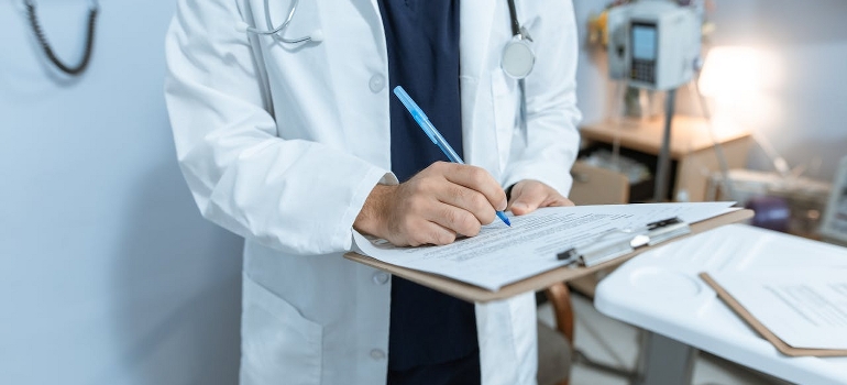 A doctor is writing on a medical chart.