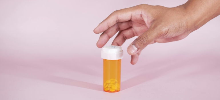 A person reaching for a yellow bottle of medicine