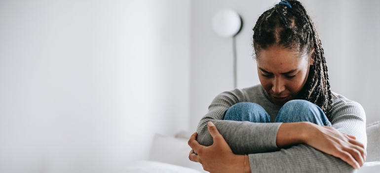 An anxious woman sitting and holding her knees