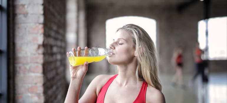 A woman is drinking a juice.