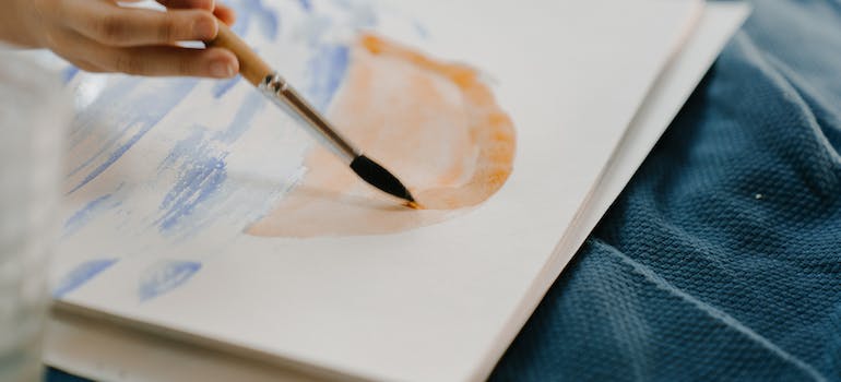 A hand holding a brush and painting while reflecting inner thoughts through art therapy