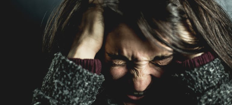 upset woman holding her head and frowning representing the link between marijuana and schizophrenia.
