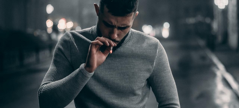 A stressed man is smoking and thinking of the neuroscience behind cravings.
