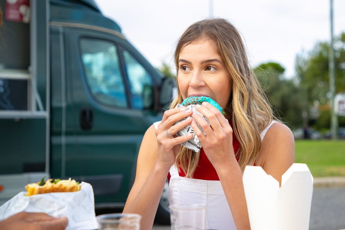 A young woman is eating in the street cafe and thinking of the neuroscience behind cravings.