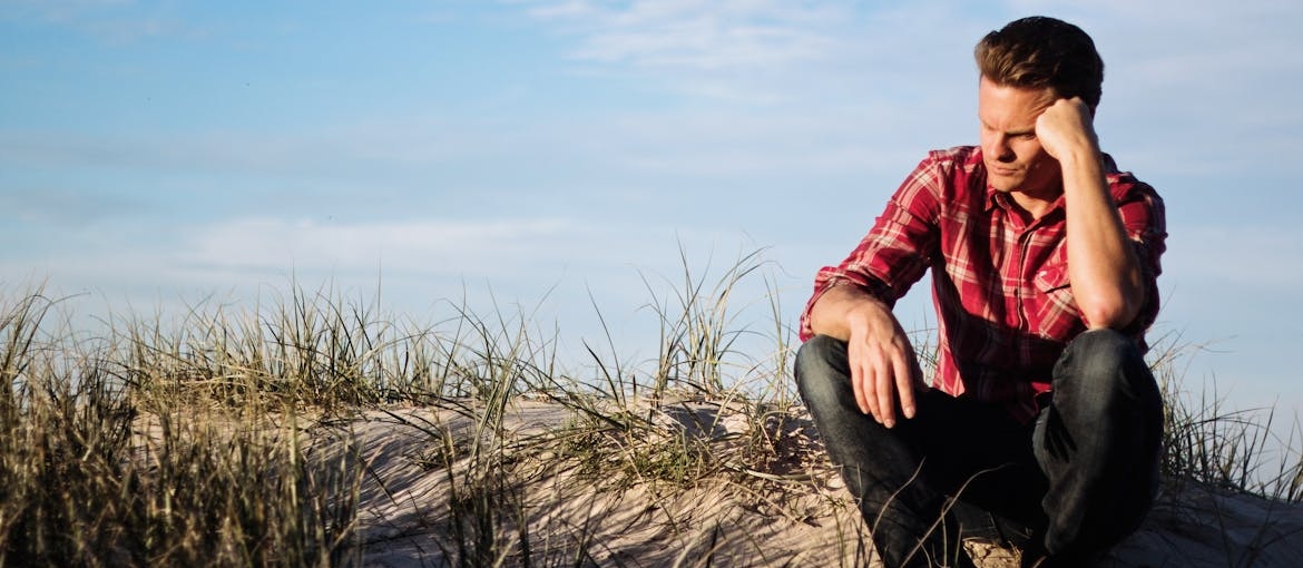 Man sitting on the ground thinking about the neuroscience behind cravings.