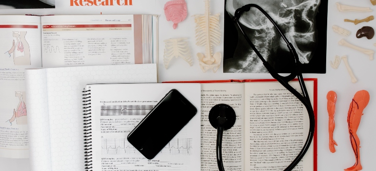 A phone and a CT scan on the table next to many books.