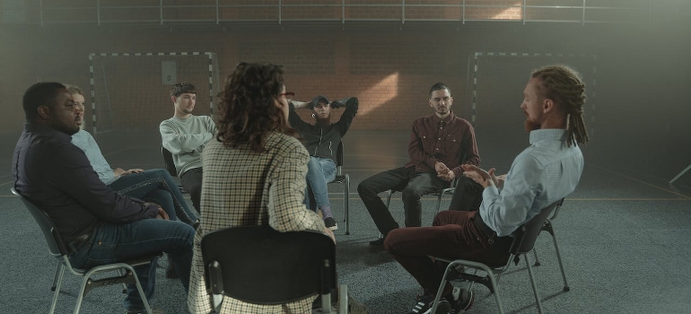 People sitting on chairs during group therapy for addiction in the first year of sobriety.