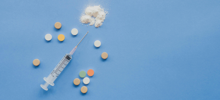 a syringe with pills around it used to administer heroin, one of the hardest drugs to quit
