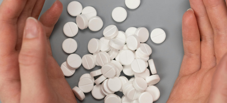 A person with a lot of white pills between their hands