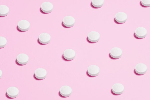 White pills on a pink background
