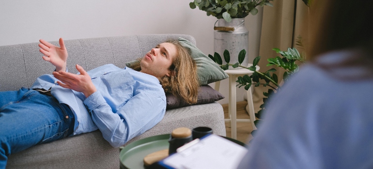A man laying on a couch while talking to a therapist