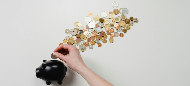 A person putting coins in a black piggy bank for handling money in addiction recovery