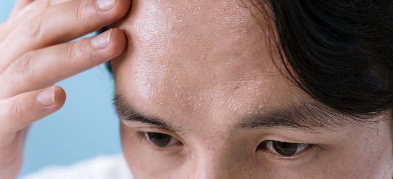 man touching his forehead seeing new wrinkles, which are one of the symptoms of how does drug abuse affect skin health.