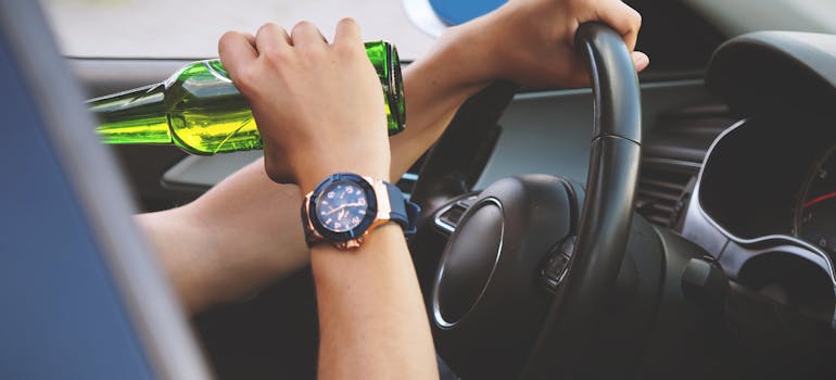 Man drinking and driving, one of the dangers of social drinking.