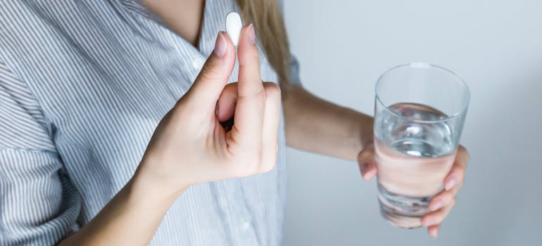 Woman taking a pill with a glass of water.