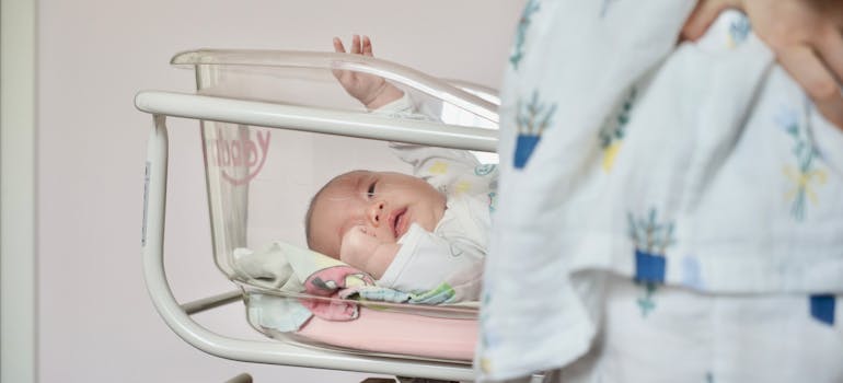 Baby laying down in a bassinet in a hospital.
