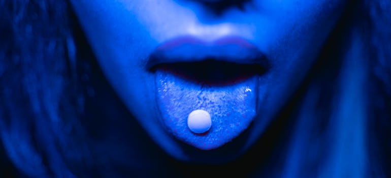 Hallucinogen pill, one of the most commonly abused drugs among millennials, on a woman's tongue.
