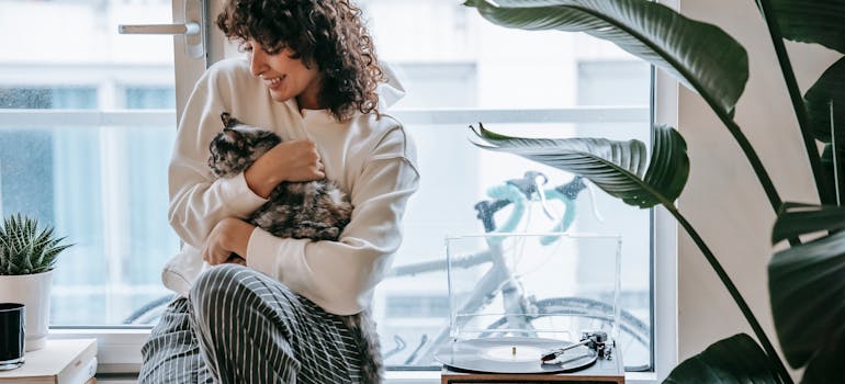 Woman sitting with her cat near a window.