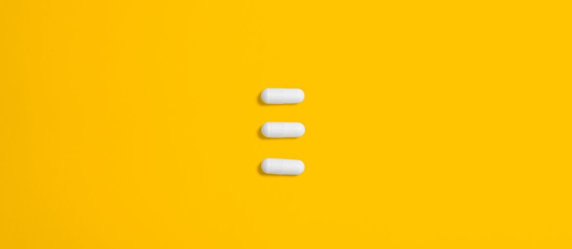 Three white pills on a yellow background.