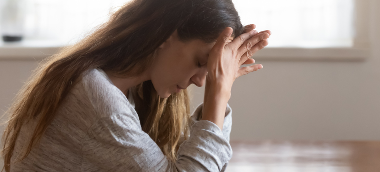 A woman in distress pushes her forehead against her hands