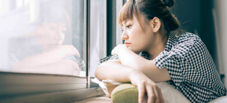 A woman looks through the window looking preoccupied