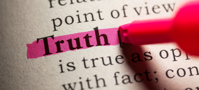 A person highlights the word true in a dictionary