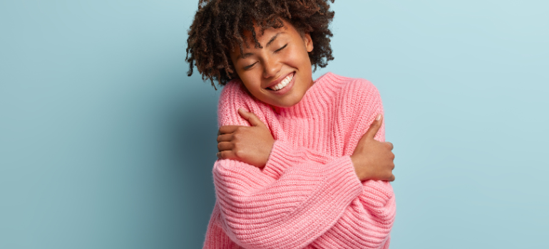 A person hugging themselves with a smile on their face