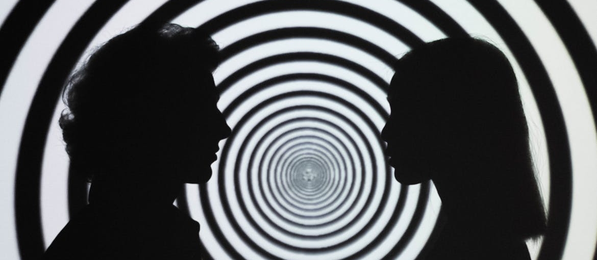 Silhouette of 2 people standing in front of white and black stripe wall symbolizing hallucinations