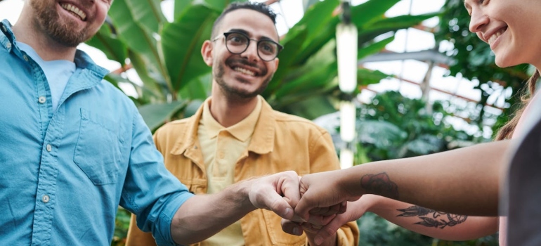 Two men and a women doing friendly fist-bump outside