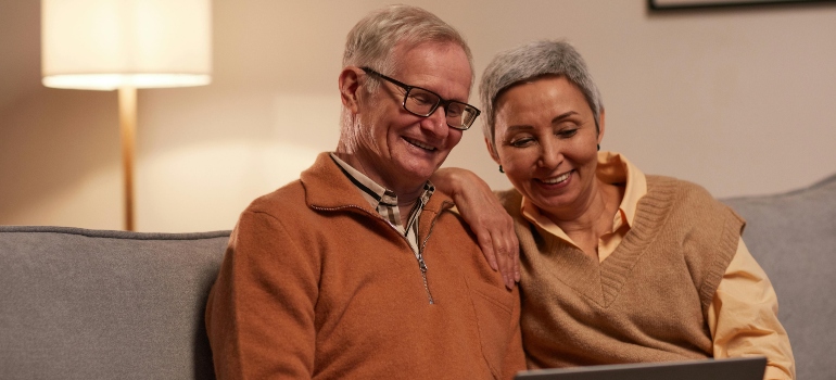 An elderly couple sitting on a sofa talking about mental health support and addiction treatment for aging adults