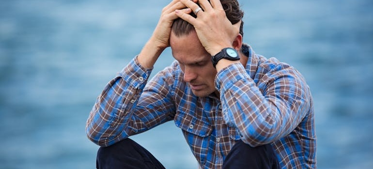 Man sitting on the ground and holding his head.