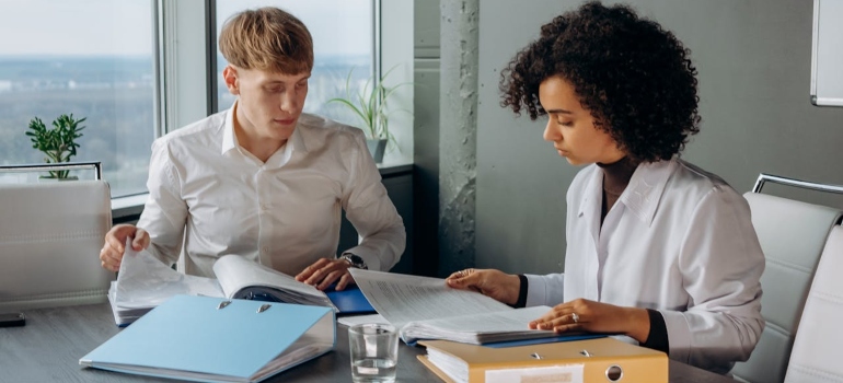 A man and a woman checking documentation in an office