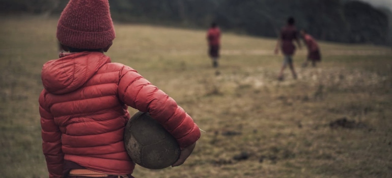 A child with a ball watching her friends from a distance