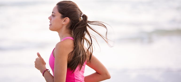 Woman in a pink top running on a beach.