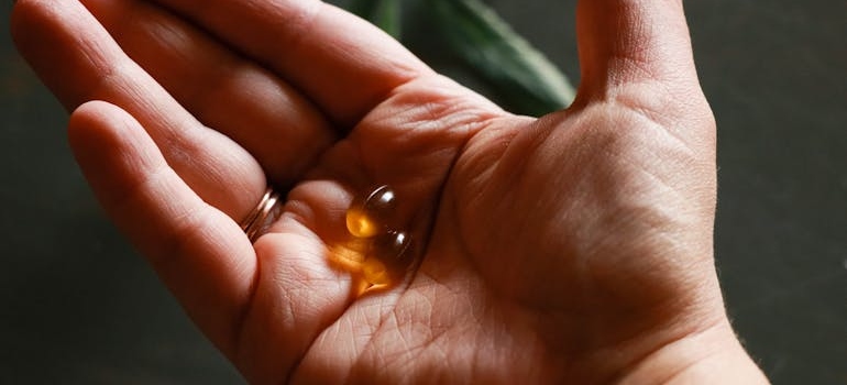 Person holding a pill in the palm of their hand.