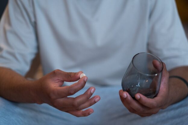 Man holding a pill and a glass.