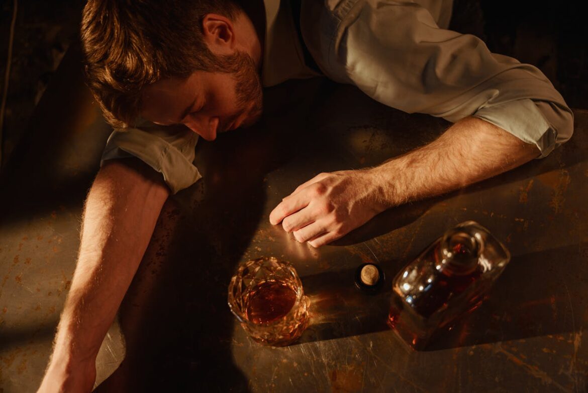 Person lying on a table while drinking whiskey.