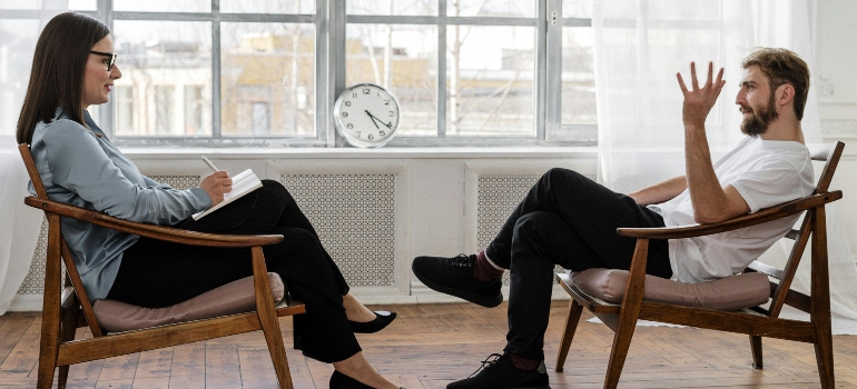 The man and the woman are sitting in the chair and talking about how to choose the right Barbiturate rehab center.