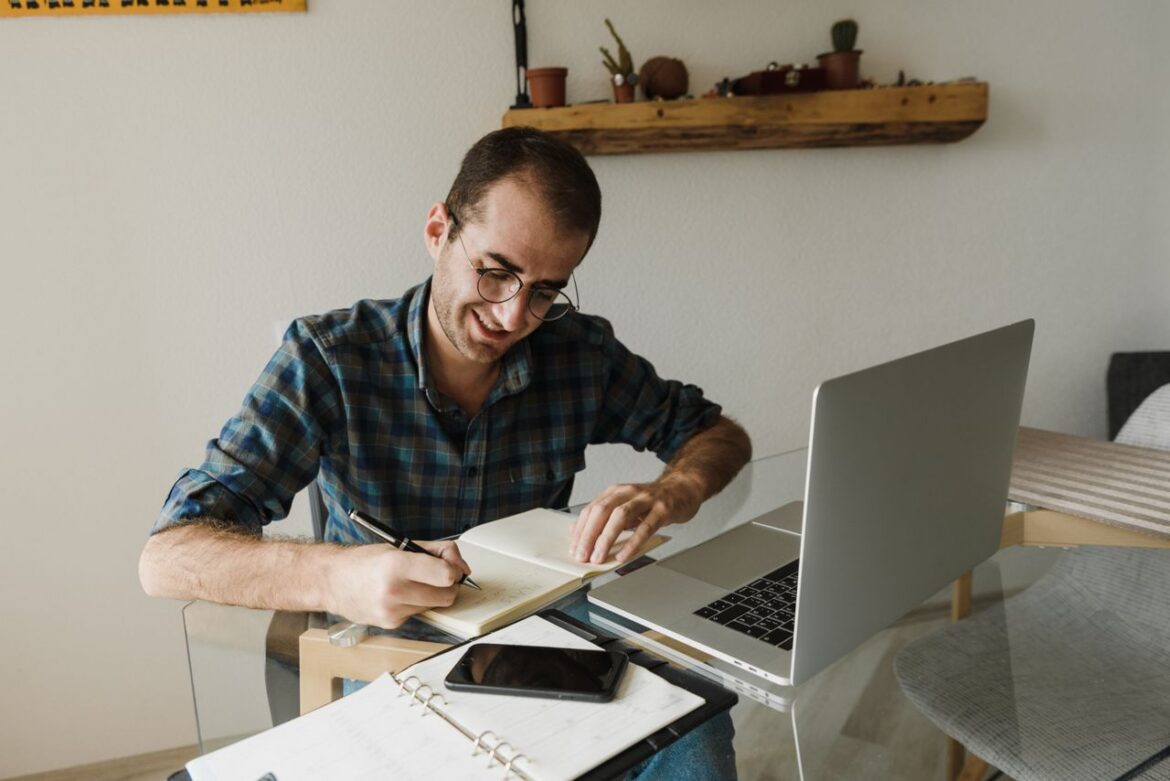 Man wearing glasses writing notes while career planning after addiction.