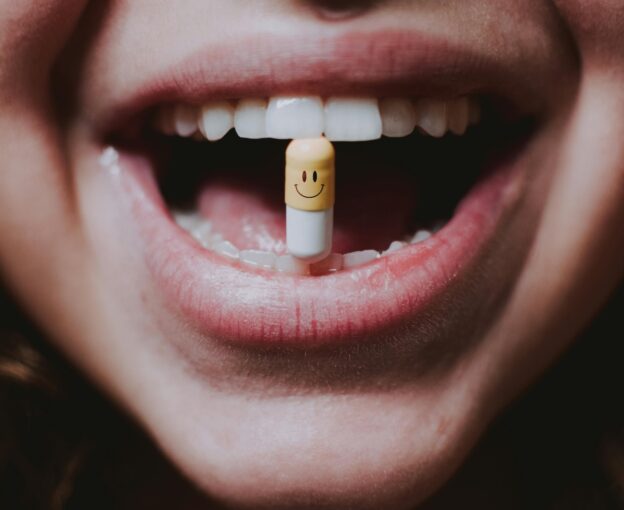 A woman is holding a pill between her teeth.
