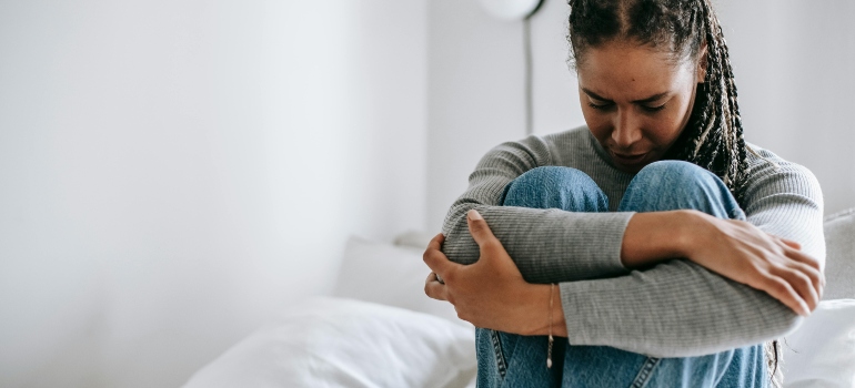 A depressed woman is sitting on the couch.