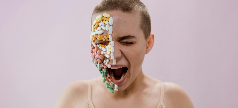 A screaming woman is covered with pills across her face.